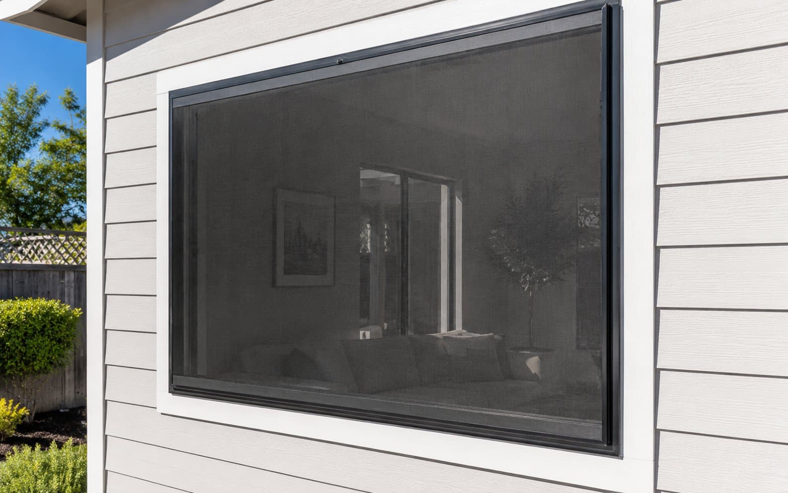 Exterior solar screen installed on a large window, black aluminum frame with interior visible through the mesh